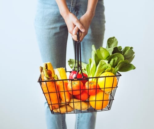 Consumer with a shopping basket full of fruits and vegetables